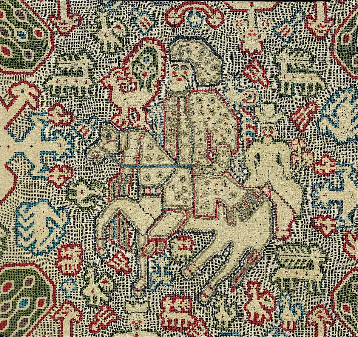 Cojín decorativo con escena bordada en punto de cruz.